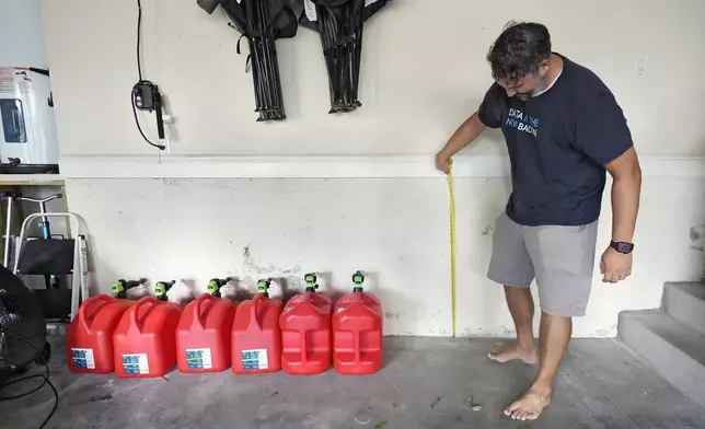 Chris Sundar measures the depth of floodwaters from Hurricane Milton in his garage Sunday, Oct. 13, 2024, in Tampa, Fla. (AP Photo/Chris O'Meara)