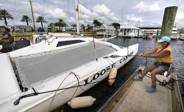 Captain D.J. McCabe helps batten down a catamaran at the Downtown Sanford Marina on Lake Monroe in Sanford, Fla., Tuesday, Oct. 8, 2024, in preparation for the impact of Hurricane Milton. (Joe Burbank/Orlando Sentinel via AP)