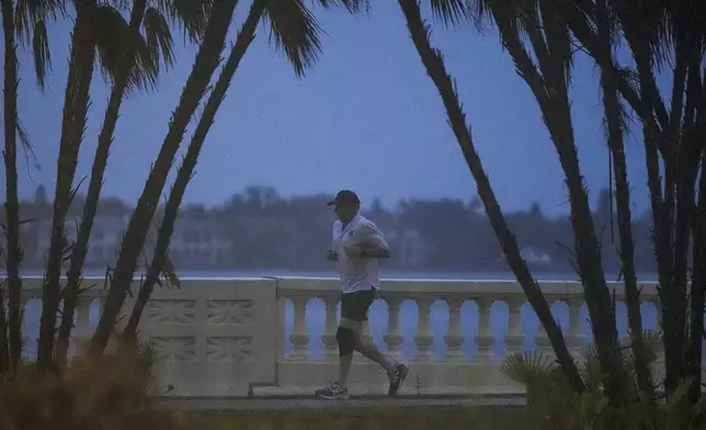 A jogger runs along the bay in heavy rain ahead of Hurricane Milton, Wednesday, Oct. 9, 2024, in Tampa, Fla. (AP Photo/Mike Stewart)