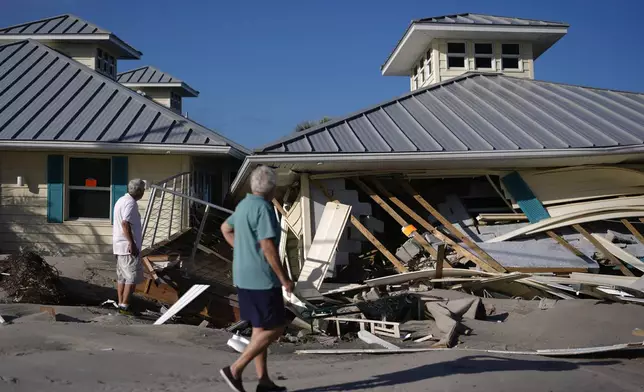 Property owners who preferred not to be named assess damage to their home and business, which bears orange notices calling for demolition, after the passage of Hurricane Milton, on Manasota Key in Englewood, Fla., Sunday, Oct. 13, 2024. (AP Photo/Rebecca Blackwell)