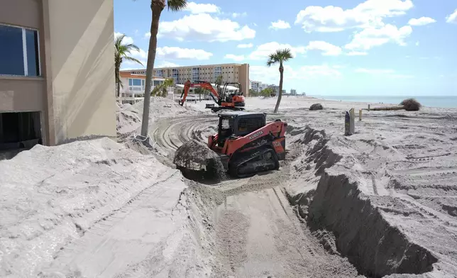 Scott Bennett, a contractor who specializes in storm recovery, uses a skid steer to remove sand around 5 feet deep from the patio of a beachfront condominium in Venice, Fla., following the passage of Hurricane Milton, Saturday, Oct. 12, 2024. (AP Photo/Rebecca Blackwell)