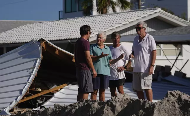 Property owners speak together as they process the damage to their homes and community following Hurricane Milton, on Manasota Key, in Englewood, Fla., Sunday, Oct. 13, 2024. (AP Photo/Rebecca Blackwell)