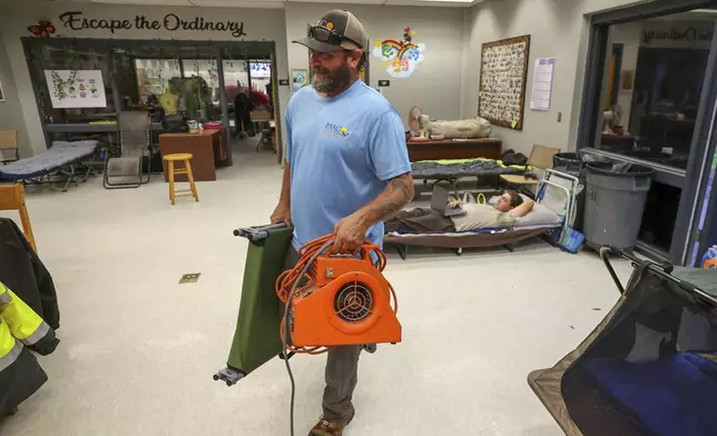 Mike Ketchum brings in equipment to set up for sleeping in a classroom at a hurricane shelter at River Ridge Middle/High School in preparation for Hurricane Milton, Wednesday, Oct. 9, 2024, in New Port Richey, Fla. (AP Photo/Mike Carlson)