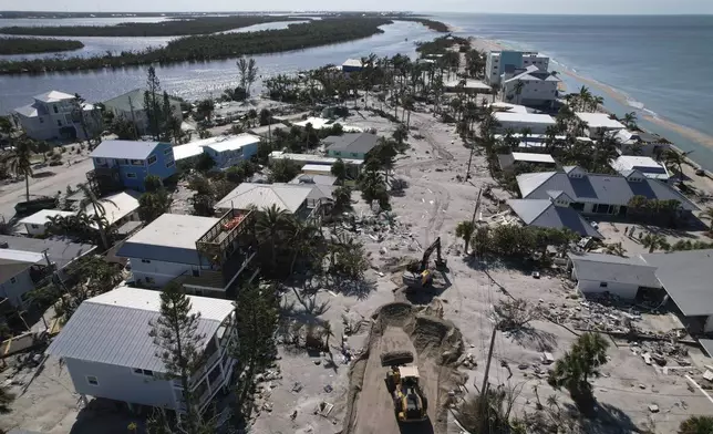 Charlotte County workers clear feet of sand from the main road on southern Manasota Key, in Englewood, Fla., following the passage of Hurricane Milton, Sunday, Oct. 13, 2024. (AP Photo/Rebecca Blackwell)