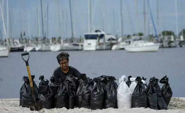 Susana Ortiz fills out sand bags on the beach at the Davis Islands Yacht Basin as she prepares for the arrival of Hurricane Milton, Tuesday, Oct. 8, 2024, in Tampa, Fla. (AP Photo/Julio Cortez)