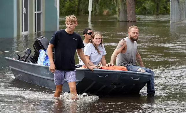 Residents along the Alafia river use a boat as transportation through floodwaters caused by Hurricane Milton Friday, Oct. 11, 2024, in Lithia, Fla. (AP Photo/Chris O'Meara)