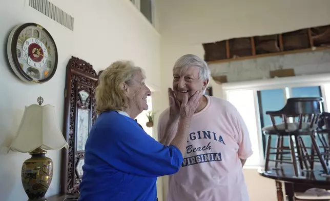 Ron and Jean Dyer, high school sweethearts who have been married for 60 years, joke together as they talk in the living room of their second-floor beachfront condominium, which lost its roof and a section of wall during Hurricane Milton, in Venice, Fla., Saturday, Oct. 12, 2024. (AP Photo/Rebecca Blackwell)