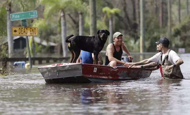 Residents ride in a boat in a neighborhood inundated by historic flooding of the Alafia River caused by Hurricane Milton on Friday, Oct. 11, 2024 in Lithia, Fla. (Luis Santana/Tampa Bay Times via AP)