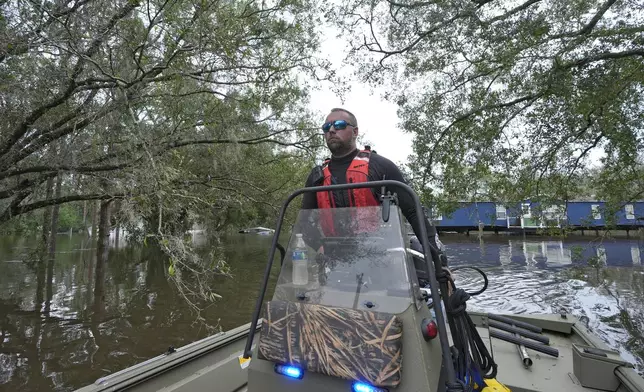 Hillsborough County Master Deputy Robert Unger guides a boat through floodwaters from Hurricane Milton along the Alafia river Friday, Oct. 11, 2024, in Lithia, Fla. (AP Photo/Chris O'Meara)