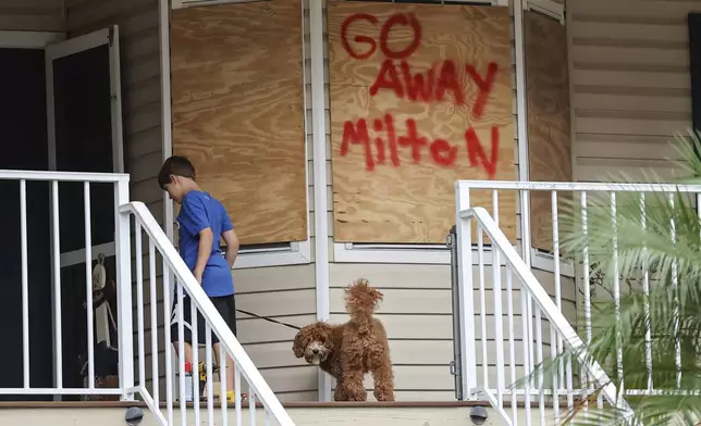 Noah Weibel and his dog Cookie climb the steps to their home as their family prepares for Hurricane Milton on Monday, Oct. 7, 2024, in Port Richey, Fla. (AP Photo/Mike Carlson)