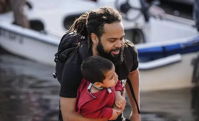 A man and child leave a rescue boat after high flood waters entered their apartment in the aftermath of Hurricane Milton, Thursday, Oct. 10, 2024, in Clearwater, Fla. (AP Photo/Mike Stewart)