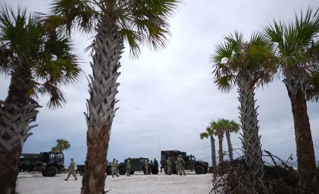 Members of the Florida Army National Guard stage on a beach as they prepare for the arrival of Hurricane Milton, in Bradenton Beach on Anna Maria Island, Fla., Tuesday, Oct. 8, 2024. (AP Photo/Rebecca Blackwell)