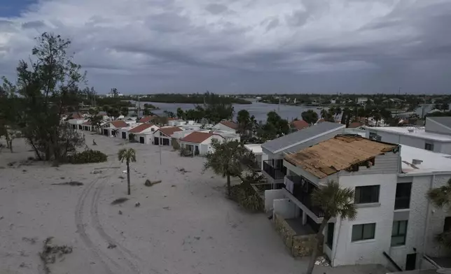 The damaged roof of Ron and Jean Dyer's beachfront condo at Bahia Vista Gulf is seen alongside the sand-swamped Jetty Villas, after the passage of Hurricane Milton, on the island of Venice, Fla., Friday, Oct. 11, 2024. (AP Photo/Rebecca Blackwell)