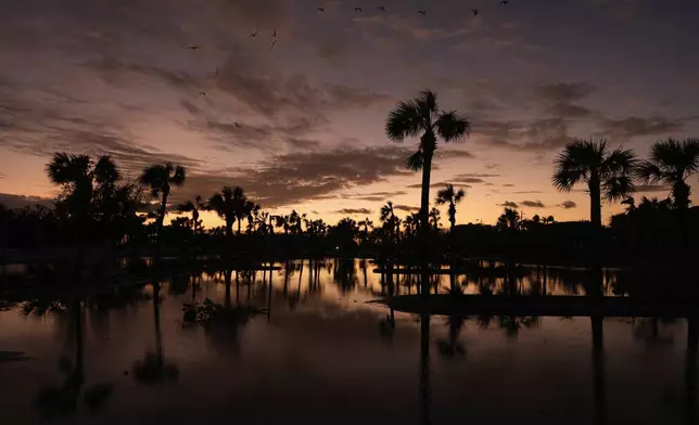 Receding flooding from Hurricane Milton reflects the sunset, in Siesta Key, Fla., Thursday, Oct. 10, 2024. (AP Photo/Rebecca Blackwell)