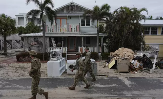 Members of the Florida Army National Guard check for any remaining residents in nearly-deserted Bradenton Beach, where piles of debris from Hurricane Helene flooding still sits outside damaged homes ahead of the arrival of Hurricane Milton, Tuesday, Oct. 8, 2024, on Anna Maria Island, Fla. (AP Photo/Rebecca Blackwell)