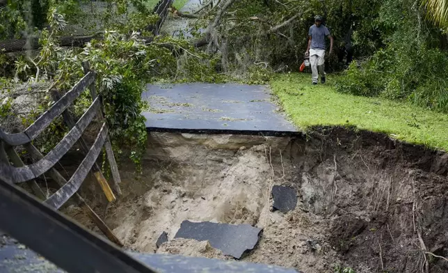 Renel Prophet carries a chainsaw to get it repaired after it broke while cleaning out down trees in his property, which became unaccessible during Hurricane Milton, Friday, Oct. 11, 2024, in Riverview, Fla. (AP Photo/Julio Cortez)