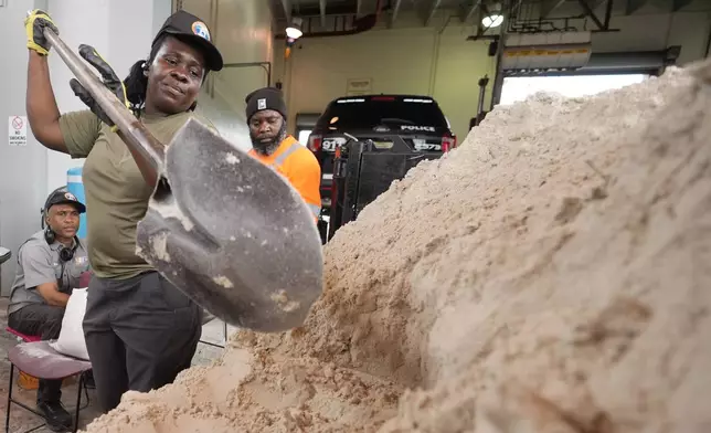 North Miami Beach, Fla., public service worker Annarose Bellefleur shovels sand as workers load sandbags, to distribute to residents to help prevent flooding, as Hurricane Milton prepares to strike Florida, Tuesday, Oct. 8, 2024, in North Miami Beach. (AP Photo/Wilfredo Lee)