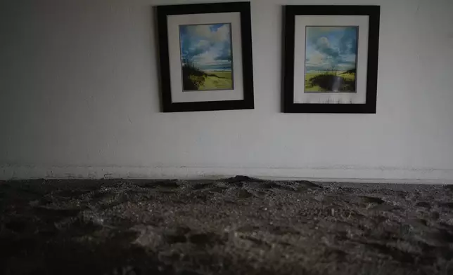 Paintings hang above several feet of sand filling a condo following the passage of Hurricane Milton, at YCA Vacation Rentals in Venice, Fla., Friday, Oct. 11, 2024. (AP Photo/Rebecca Blackwell)