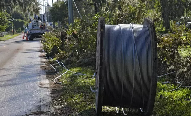 A large spool of electrical wire sits among Hurricane Milton debris as linemen from Pike Corporation, of North Carolina, fix wires Sunday, Oct. 13, 2024, in Valrico, Fla. (AP Photo/Chris O'Meara)