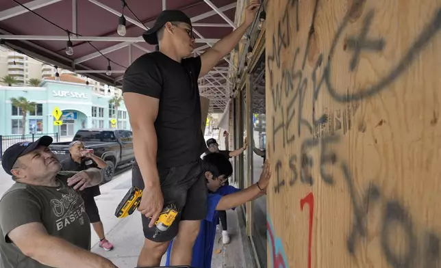 Workers outside Toucans Bar and Grill board up the restaurant Monday, Oct. 7, 2024, in Clearwater Beach, Fla., ahead of the possible arrival of Hurricane Milton. (AP Photo/Chris O'Meara)