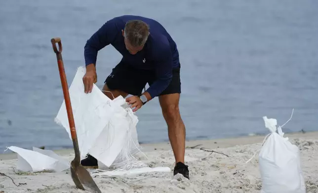 A person fills sand bags on the beach at the Davis Islands Yacht Basin while preparing for the arrival of Hurricane Milton, Tuesday, Oct. 8, 2024, in Tampa, Fla. (AP Photo/Julio Cortez)