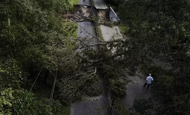 Del Ockey, a seasonal Florida resident from Canada, walks near the damaged bridge that leads onto his property during Hurricane Milton, Friday, Oct. 11, 2024, in Riverview, Fla. (AP Photo/Julio Cortez)