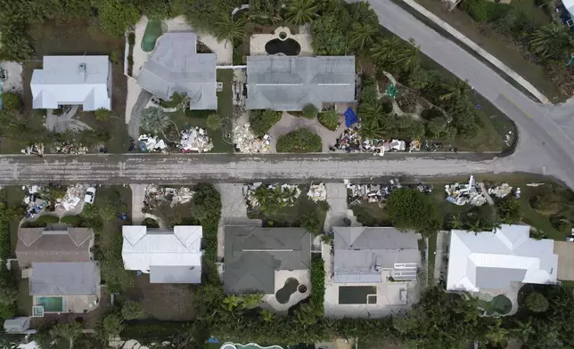 In this image taken with a drone, piles of furniture and household items destroyed in Hurricane Helene flooding sit piled up outside of homes ahead of the arrival of Hurricane Milton, Tuesday, Oct. 8, 2024, in Holmes Beach on Anna Maria Island, Fla. (AP Photo/Rebecca Blackwell)