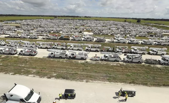 Linemen gather in front of hundreds of utility trucks staged, Tuesday, Oct. 8, 2024. at The Villages, Fla. in preparation for Hurricane Milton.(Stephen M. Dowell/Orlando Sentinel via AP)