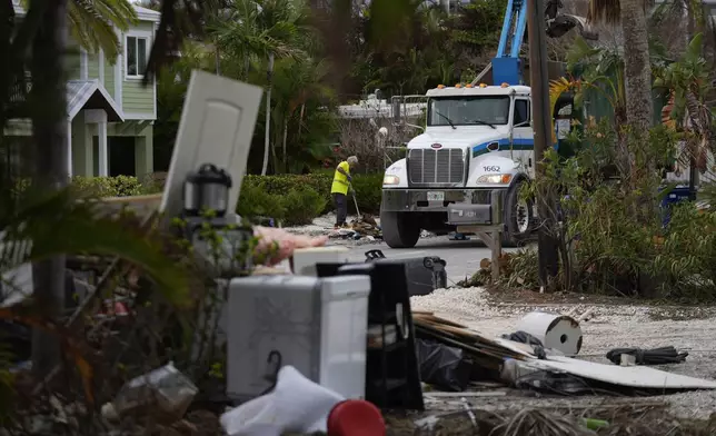 Teams work to clean up debris from Hurricane Helene flooding ahead of the arrival of Hurricane Milton, in Holmes Beach on Anna Maria Island, Fla., Tuesday, Oct. 8, 2024. (AP Photo/Rebecca Blackwell)