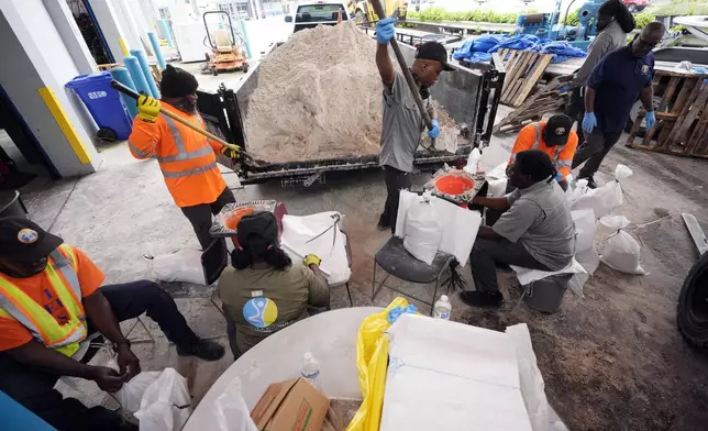 North Miami Beach, Fla., public service workers fill sandbags, to distribute to residents to help prevent flooding, as Hurricane Milton prepares to strike Florida, Tuesday, Oct. 8, 2024, in North Miami Beach. (AP Photo/Wilfredo Lee)