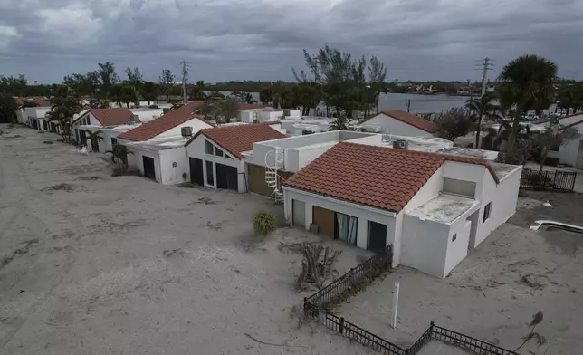 Sand swept by Hurricane Milton reaches half-way up the sliding doors of a beachfront villa, next to a pool deck where the 8 1/2 foot deep pool had disappeared under sand, at Jetty Villas on the island of Venice, Fla., Friday, Oct. 11, 2024. (AP Photo/Rebecca Blackwell)