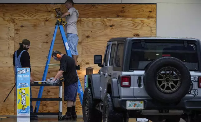 People board up a convenience store ahead of Hurricane Milton, Wednesday, Oct. 9, 2024, in Brandon, Fla. (AP Photo/Mike Stewart)