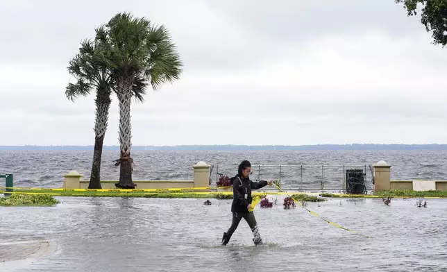 City employee Ebony Pizarro blocks off a flooded street near Lake Monroe after Hurricane Milton passed through Thursday, Oct. 10, 2024, in Sanford, Fla. (AP Photo/John Raoux)