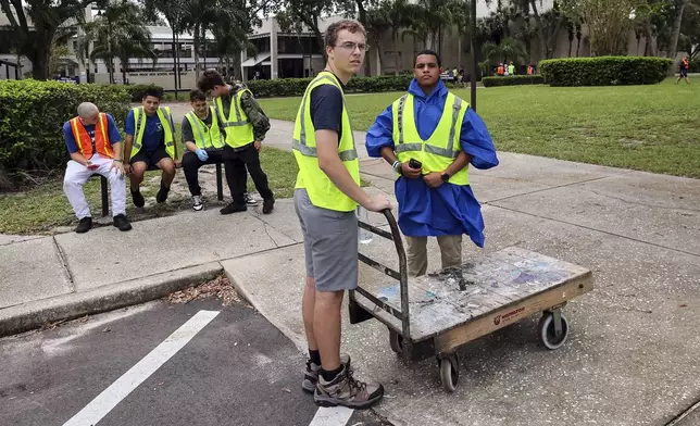 Members of the AFJROTC squadron of River Ridge High School stage to help evacuees load in as the school is ready for use as a shelter in preparation for Hurricane Milton on Monday, Oct. 7, 2024, in New Port Richey, Fla. (AP Photo/Mike Carlson)