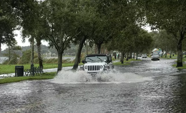 A vehicle makes its way along a street flooded by Hurricane Milton near Fort Mellon Park Thursday, Oct. 10, 2024, in Sanford, Fla. (AP Photo/John Raoux)