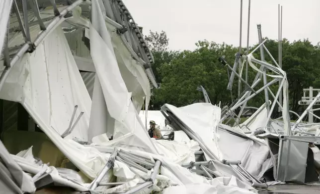 FILE - A fire fighter, center, stands surrounded by the collapsed canopy that covered the Dallas Cowboys indoor practice facility in Irving, Texas, on May 2, 2009. (AP Photo/Tony Gutierrez, File)