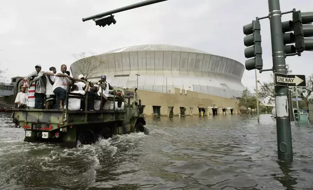 FILE - National Guard trucks haul residents through floodwaters to the Superdome after Hurricane Katrina hit in New Orleans, Aug. 30, 2005. (AP Photo/Eric Gay, File)