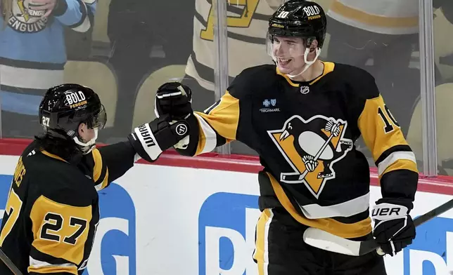 Pittsburgh Penguins' Drew O'Connor (10) celebrates with Ryan Graves (27) after scoring during the first period of an NHL hockey game against the Carolina Hurricanes, Friday, Oct. 18, 2024, in Pittsburgh. (AP Photo/Matt Freed)