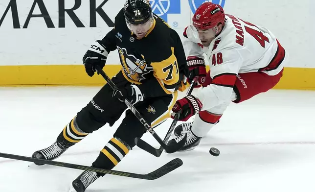 Pittsburgh Penguins' Evgeni Malkin (71) reaches for the puck against Carolina Hurricanes' Jordan Martinook (48) during the first period of an NHL hockey game, Friday, Oct. 18, 2024, in Pittsburgh. (AP Photo/Matt Freed)