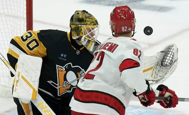 Pittsburgh Penguins goaltender Joel Blomqvist (30) reaches to make a save against Carolina Hurricanes' Jesperi Kotkaniemi (82) during the first period of an NHL hockey game, Friday, Oct. 18, 2024, in Pittsburgh. (AP Photo/Matt Freed)