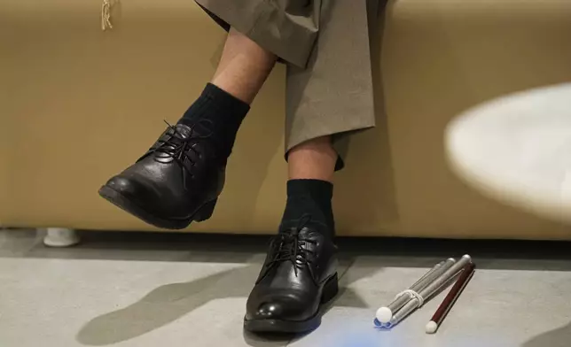 A white cane lies on floor next to Takosangba Jamir, 27, a blind pianist, as he waits for his performance at the two-day Brillante Piano Festival in Bengaluru, India, Sunday, Sept. 29, 2024. (AP Photo/Aijaz Rahi)