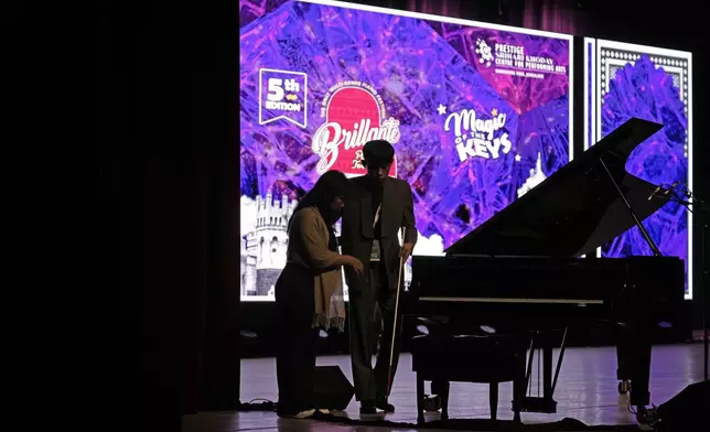 Imlibenla Jamir, 30, left, guides her brother Takosangba Jamir, 27, a blind pianist, to the stage for his performance at the two-day Brillante Piano Festival in Bengaluru, India, Sunday, Sept. 29, 2024. (AP Photo/Aijaz Rahi)