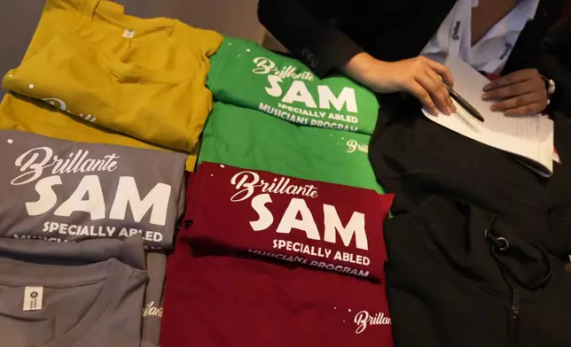 T-shirts featuring Specially Abled Musicians (SAM) program logos are displayed for sale outside an auditorium at the two-day Brillante Piano Festival in Bengaluru, India, Sunday, Sept. 29, 2024. (AP Photo/Aijaz Rahi)