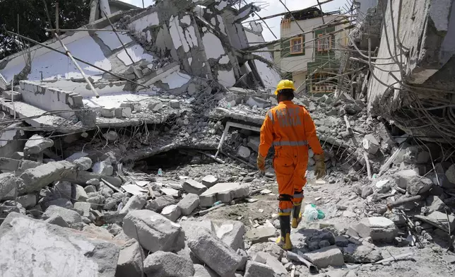 A rescue worker walks to look for the trapped survivors under the debris of an under-construction building that collapsed on Tuesday, following heavy rains in Bengaluru, India, Wednesday, Oct. 23, 2024. (AP Photo/Aijaz Rahi)