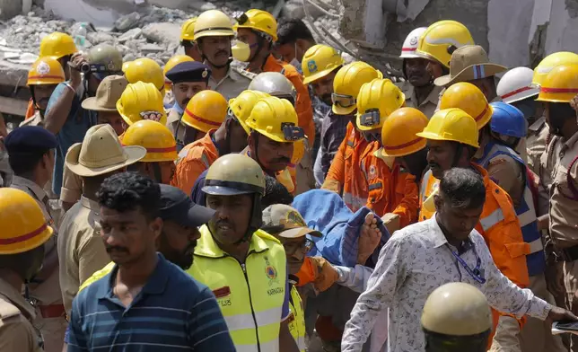 Rescue workers carry a body after recovering it from the debris of an under-construction building that collapsed on Tuesday, following heavy rains in Bengaluru, India, Wednesday, Oct. 23, 2024. (AP Photo/Aijaz Rahi)