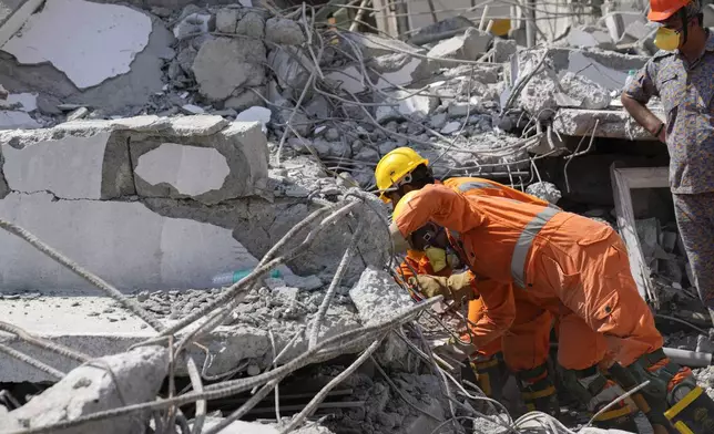 Rescue workers look for the trapped survivors under the debris of an under-construction building that collapsed on Tuesday, following heavy rains in Bengaluru, India, Wednesday, Oct. 23, 2024. (AP Photo/Aijaz Rahi)