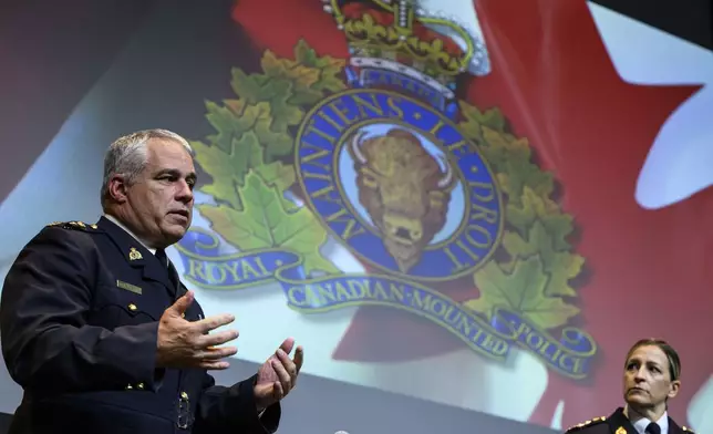 RCMP Commissioner Mike Duheme, left, speaks to a journalist as he concludes a news conference with Assistant Commissioner Brigitte Gauvin, right, at RCMP National Headquarters in Ottawa, Ontaio, Monday, Oct. 14, 2024. (Justin Tang/The Canadian Press via AP)