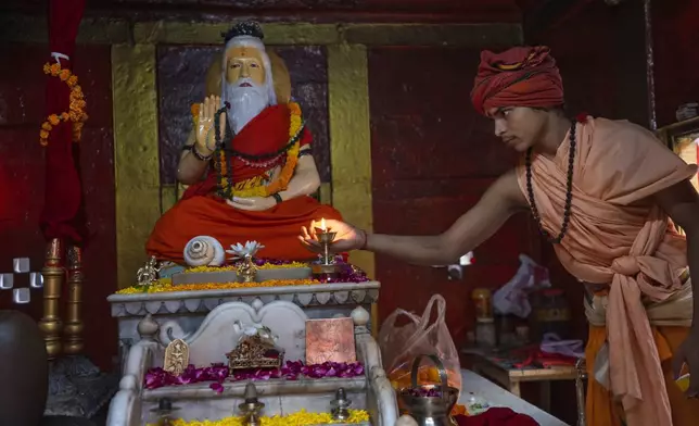 A young Hindu holy man performs an evening ritual in front of their Guru Bhagwan Sri Guru Kapil Mahamuni in Shri Panchayati Akhada Mahanirvani at Prayagraj in the northern Indian state of Uttar Pradesh, India, Thursday, Oct. 17, 2024. (AP Photo/Rajesh Kumar Singh)