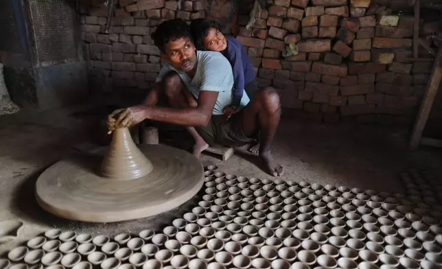 FILE- An Indian potter makes earthen lamps ahead of Diwali festival in Prayagraj, India, Oct. 27, 2021. (AP Photo/Rajesh Kumar Singh, File)