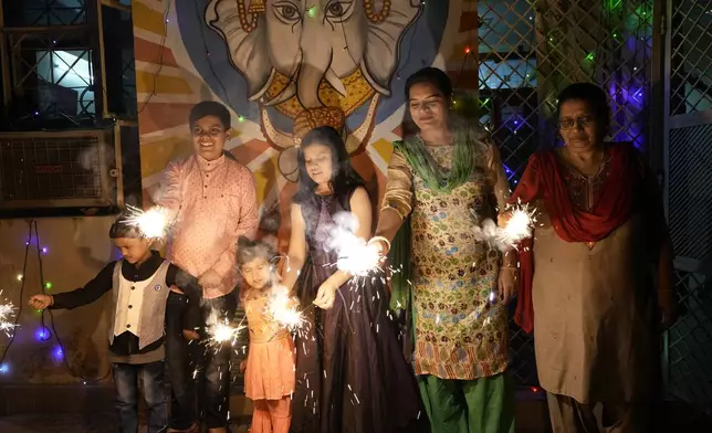 FILE- An Indian family lights firecrackers to celebrate Diwali, the Hindu festival of lights, in Prayagraj, in the northern state of Uttar Pradesh, India, Oct. 24, 2022. (AP Photo/Rajesh Kumar Singh, File)